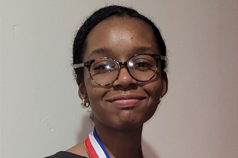 A young woman wearing glasses is smiling