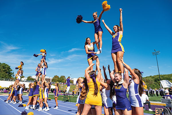 The WCU cheerleaders are in the middle of a routine, they are performing a stunt where there are three group formations each holding a flyer in the air