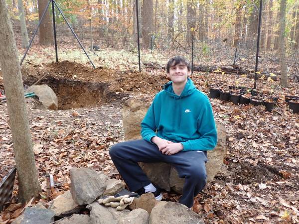 GNA Student Intern Luke Knaub sitting on a boulder that we just moved in the Native Plant Nursery