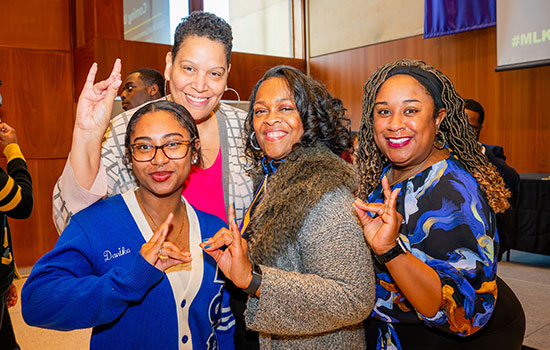 Group of 4 females holding up a hand sign